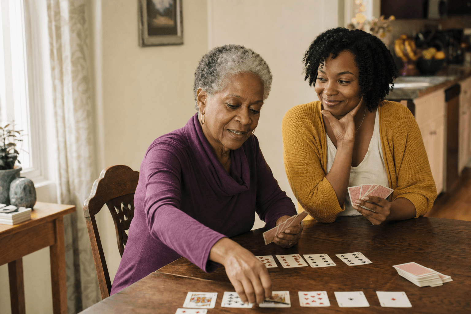 An older woman and her companion playing cards at a kitchen table